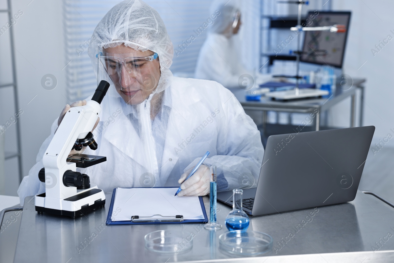 Photo of Scientist with laptop and microscope working at table in laboratory