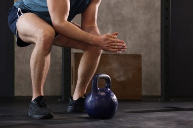 Photo of Sportsman clapping hands with talcum powder before crossfit workout with kettlebell in gym, closeup. Space for text