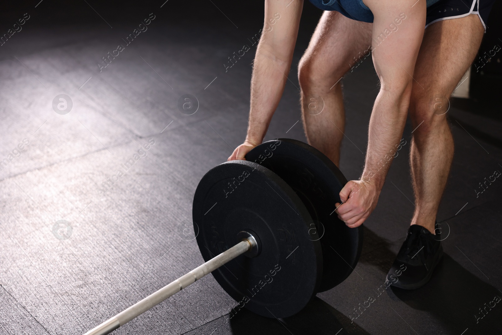 Photo of Sportsman putting weights on barbell before crossfit workout in gym, closeup. Space for text