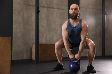 Photo of Sportsman doing kettlebell swing during crossfit workout in gym, space for text