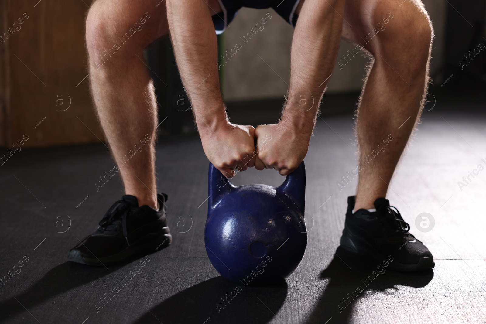 Photo of Sportsman doing kettlebell swing during crossfit workout in gym, closeup