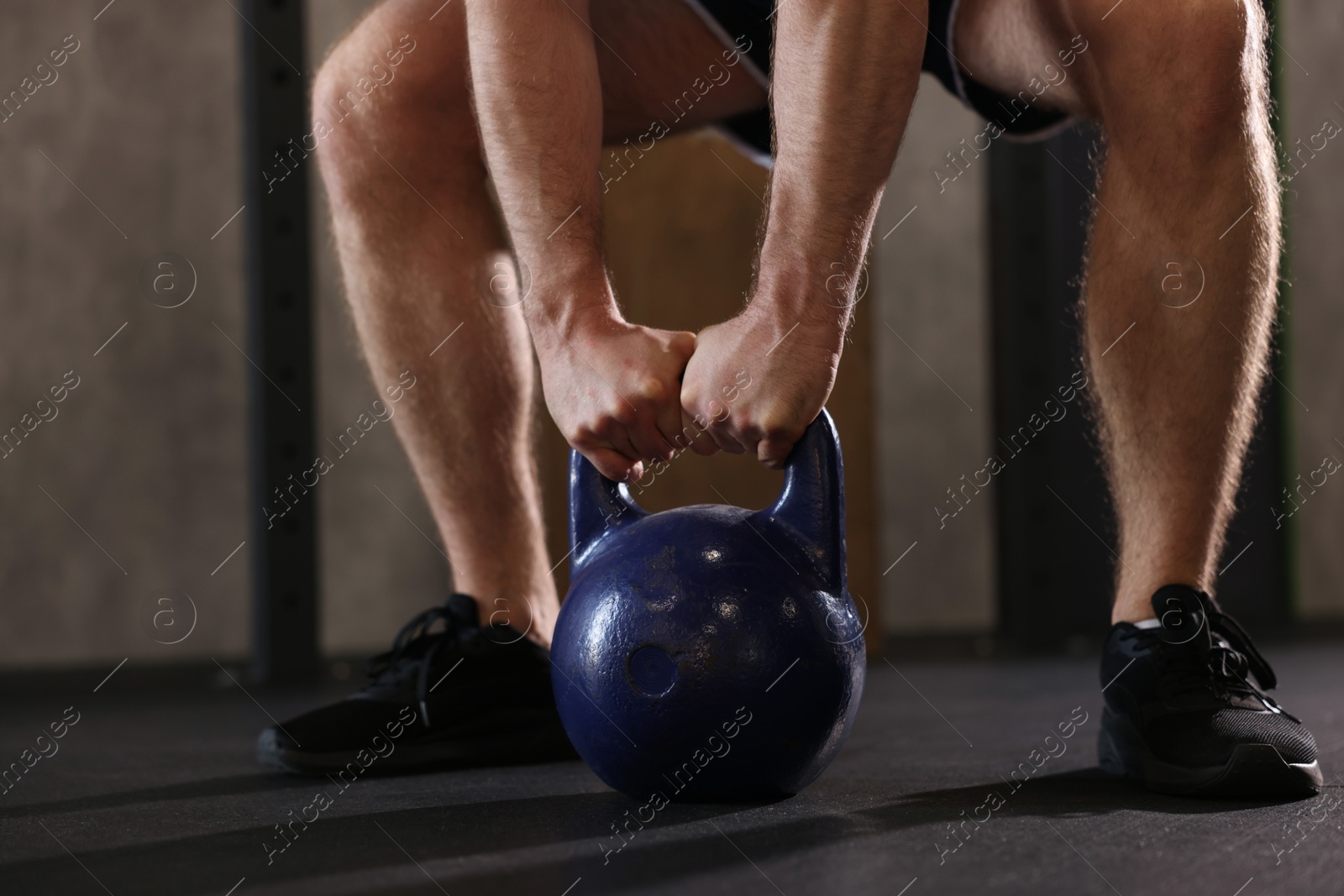 Photo of Sportsman doing kettlebell swing during crossfit workout in gym, closeup