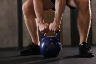 Photo of Sportsman doing kettlebell swing during crossfit workout in gym, closeup