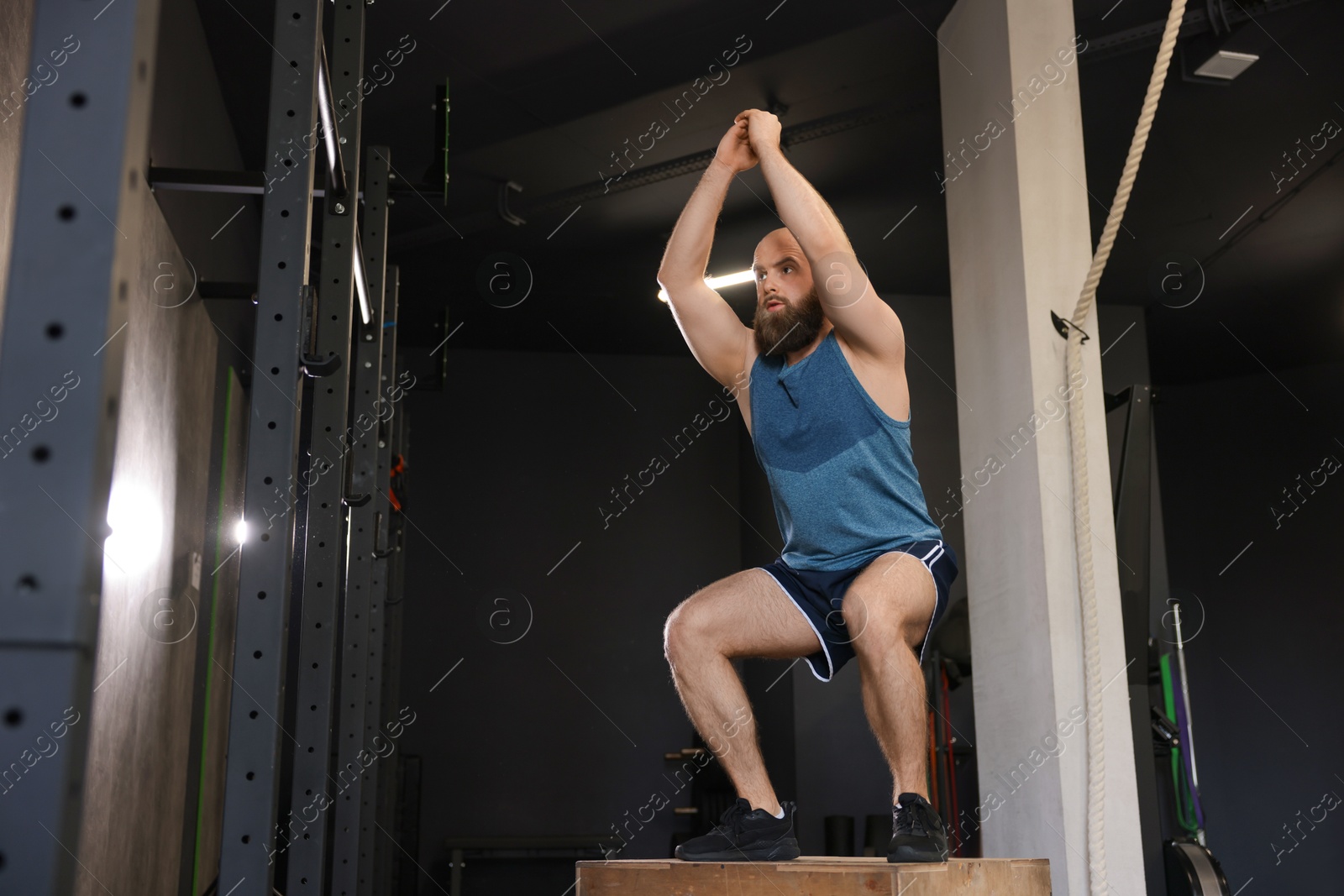 Photo of Sportsman doing box jumping during crossfit workout in gym, low angle view