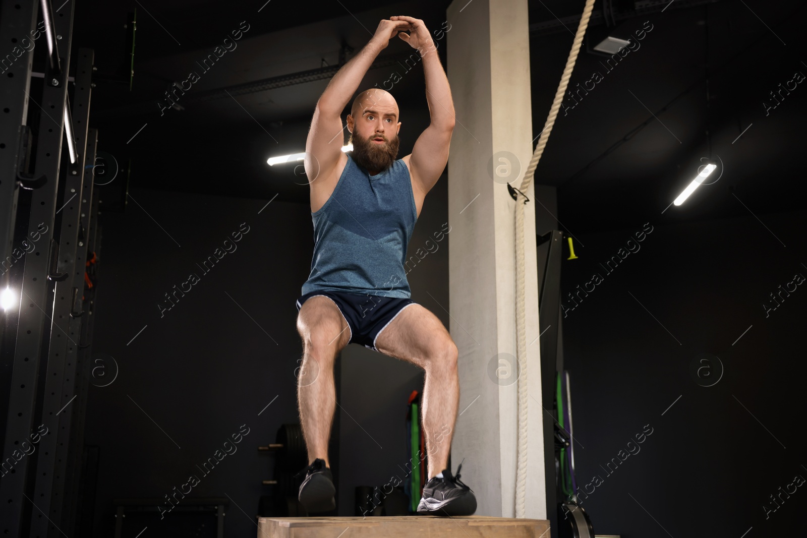 Photo of Sportsman doing box jumping during crossfit workout in gym, low angle view