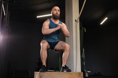 Photo of Sportsman doing box jumping during crossfit workout in gym, low angle view