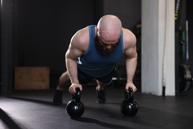 Photo of Sportsman doing kettlebell push up during crossfit workout in gym