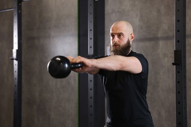 Photo of Sportsman doing kettlebell swing during crossfit workout in gym