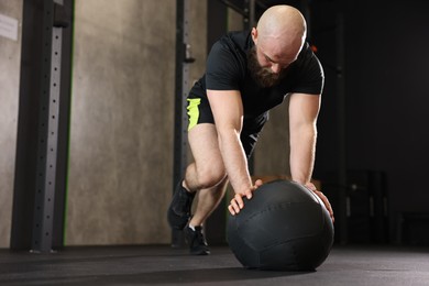 Photo of Sportsman exercising with wall ball during crossfit workout in gym. Space for text