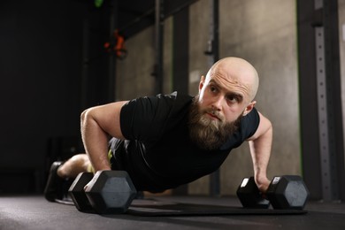 Photo of Sportsman doing dumbbell push up during crossfit workout in gym