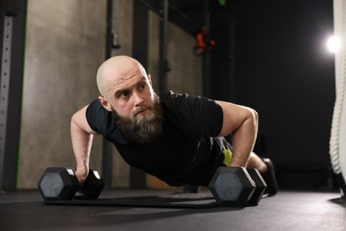 Photo of Sportsman doing dumbbell push up during crossfit workout in gym