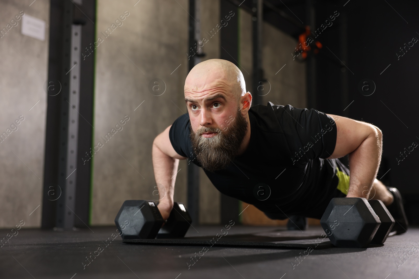 Photo of Sportsman doing dumbbell push up during crossfit workout in gym