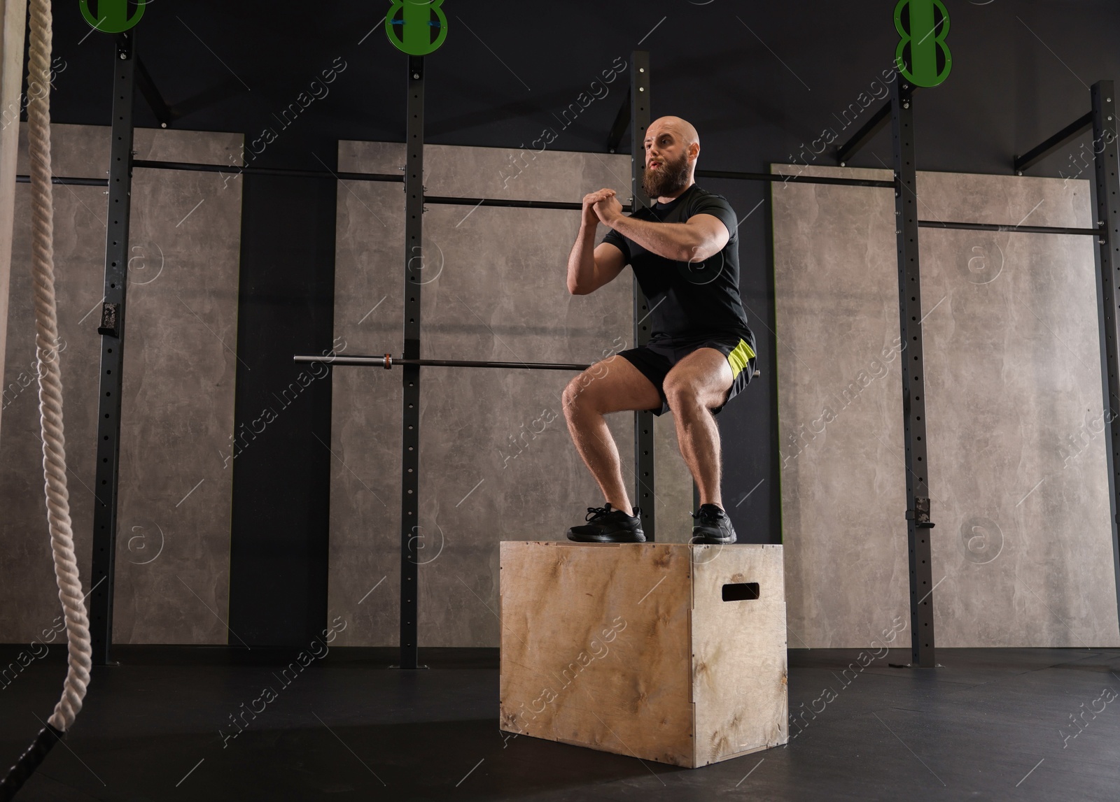 Photo of Sportsman exercising on cube during crossfit workout in gym