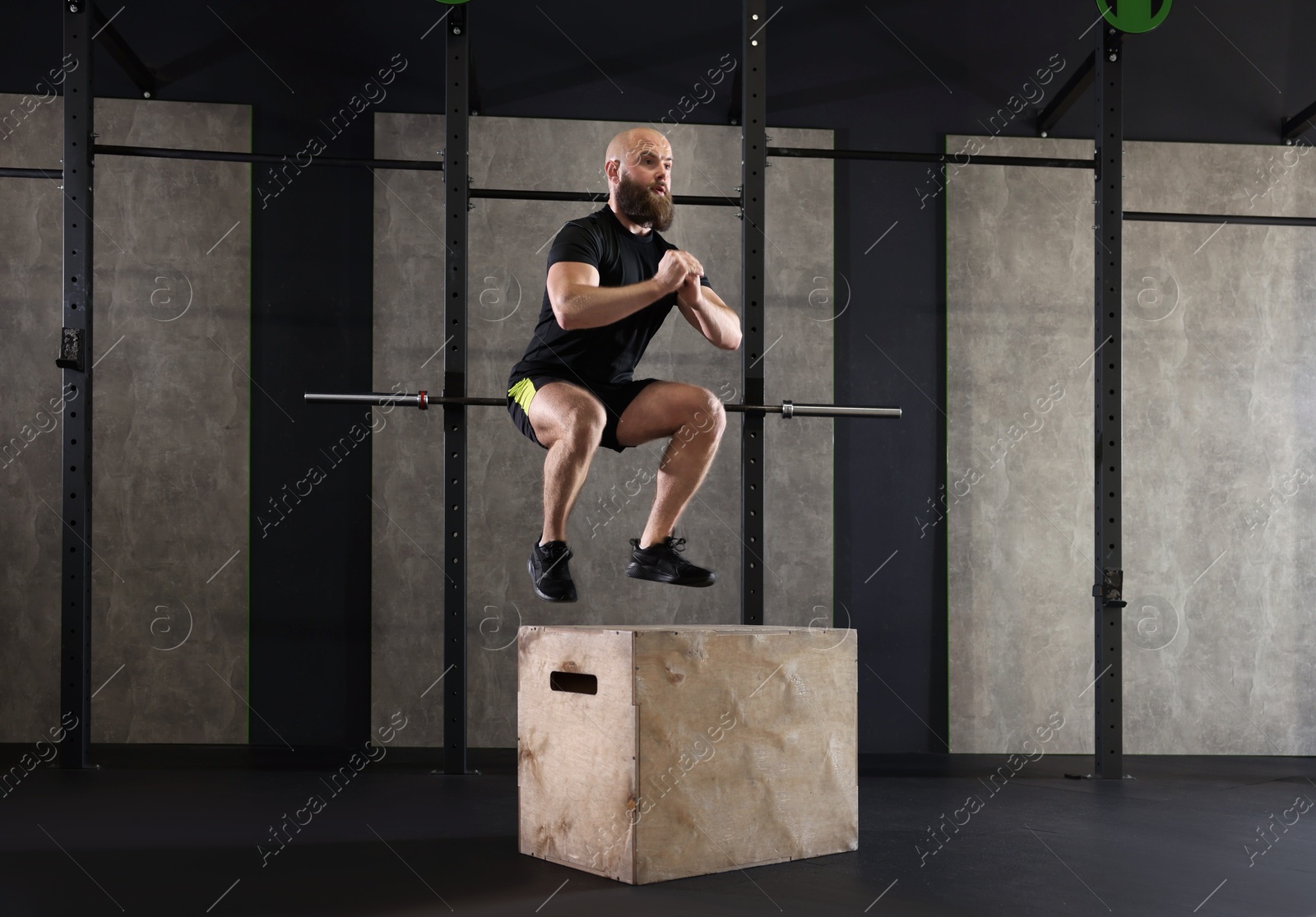 Photo of Sportsman doing box jumping during crossfit workout in gym