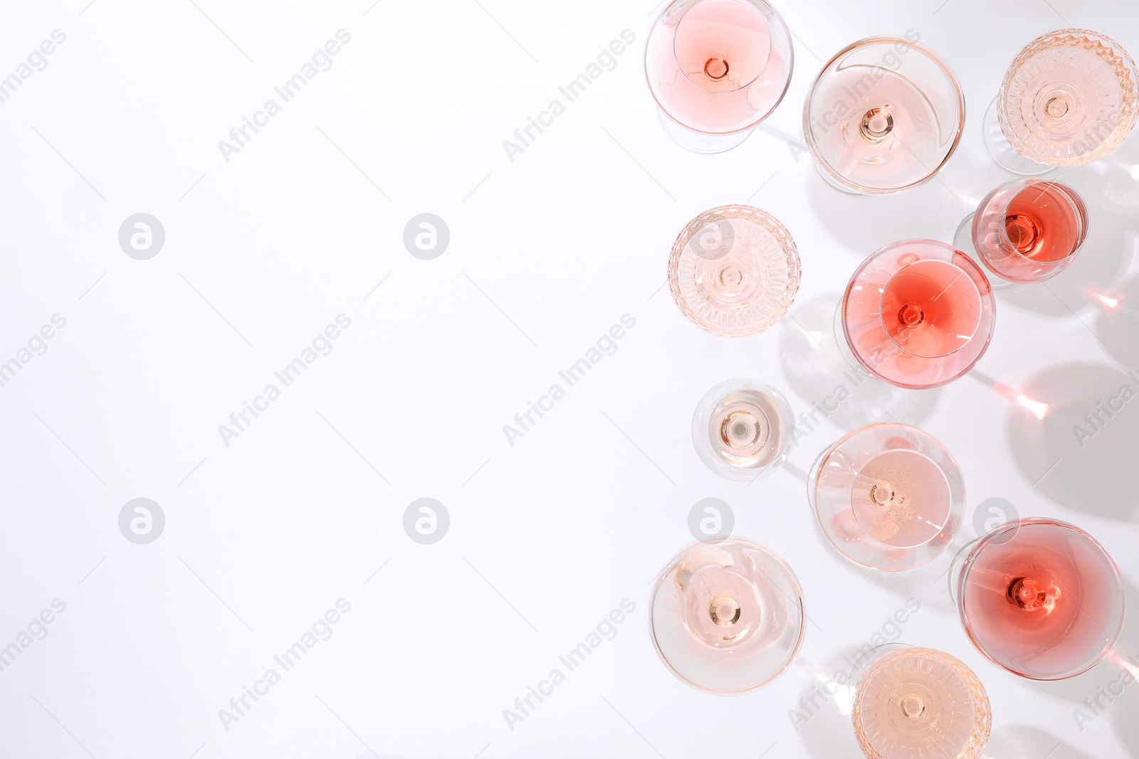 Photo of Delicious rose wine in glasses on white background, flat lay. Space for text