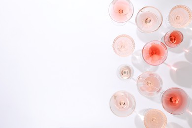 Photo of Delicious rose wine in glasses on white background, flat lay. Space for text