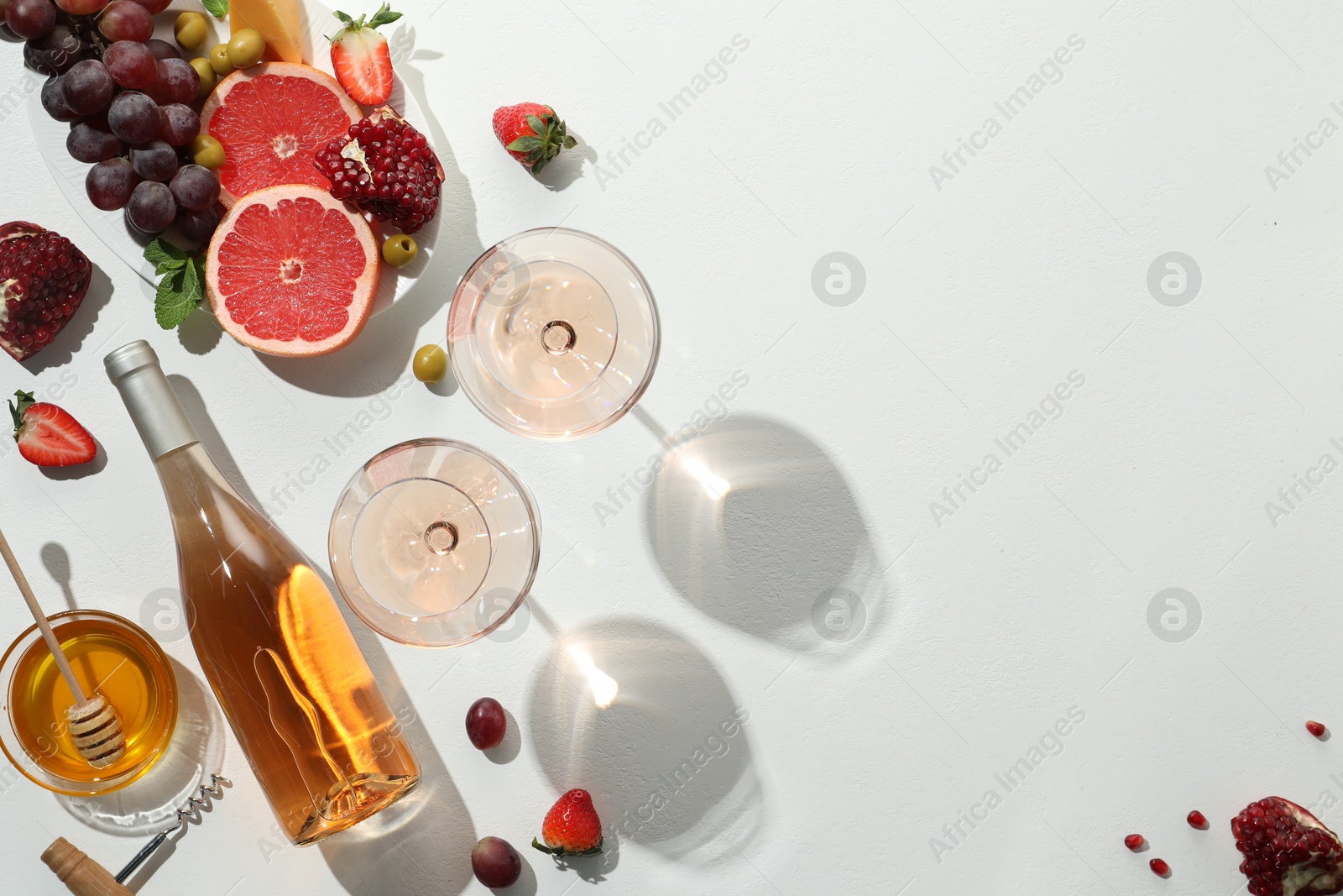 Photo of Flat lay composition with tasty rose wine and snacks on white table. Space for text