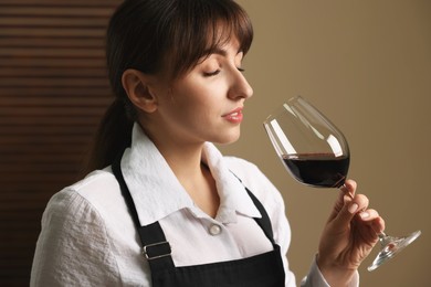 Photo of Professional sommelier tasting red wine in glass indoors