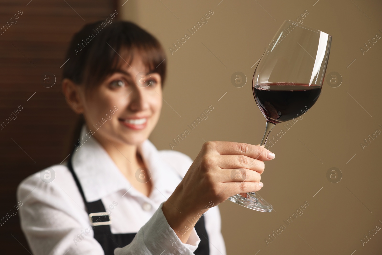 Photo of Professional sommelier analyzing quality of red wine indoors, selective focus