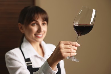 Photo of Professional sommelier analyzing quality of red wine indoors, selective focus