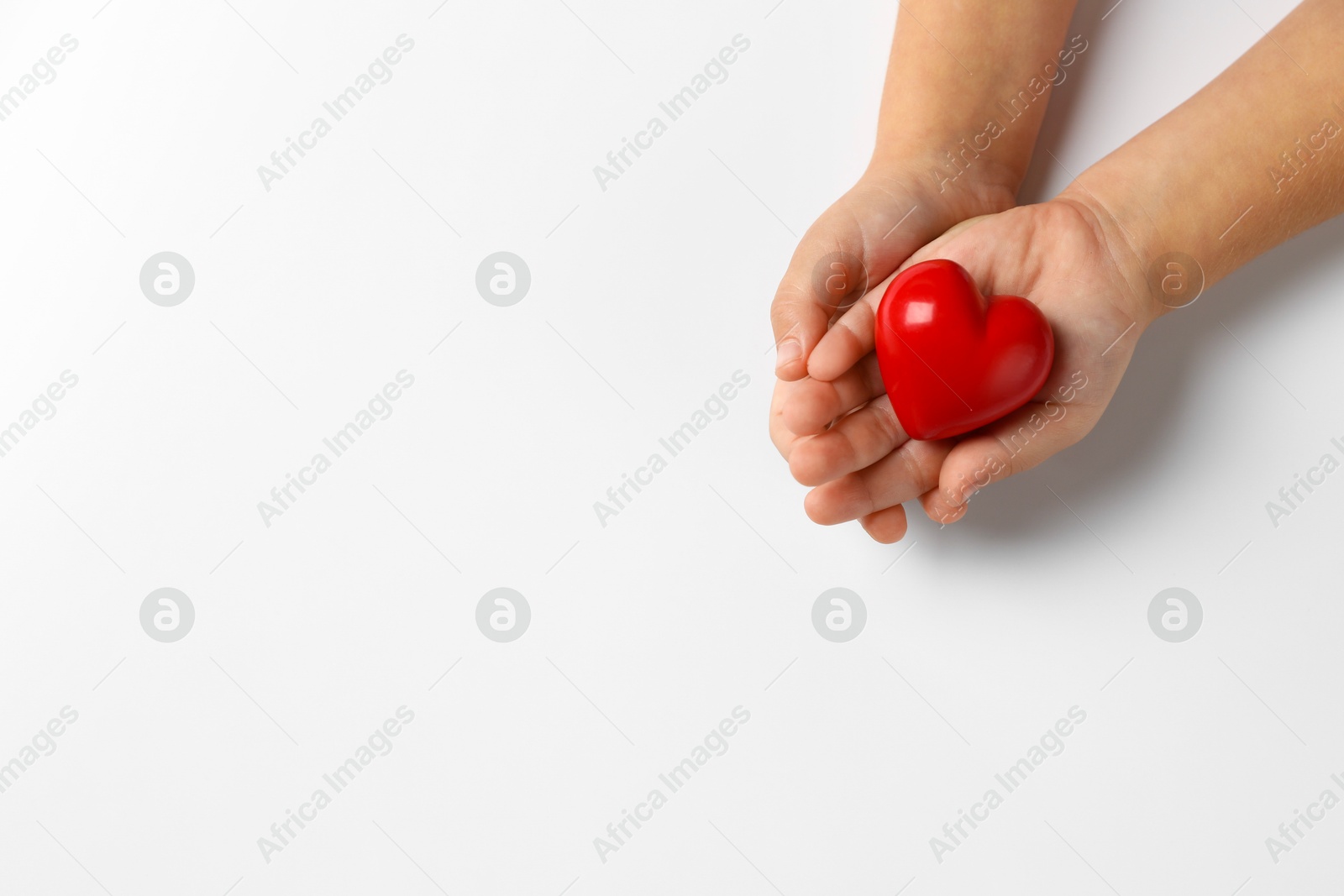 Photo of Child holding decorative red heart on white background, top view. Space for text