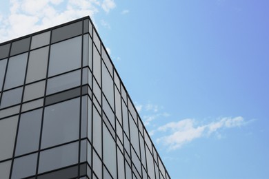 Photo of Modern building with many windows against blue sky, low angle view. Space for text