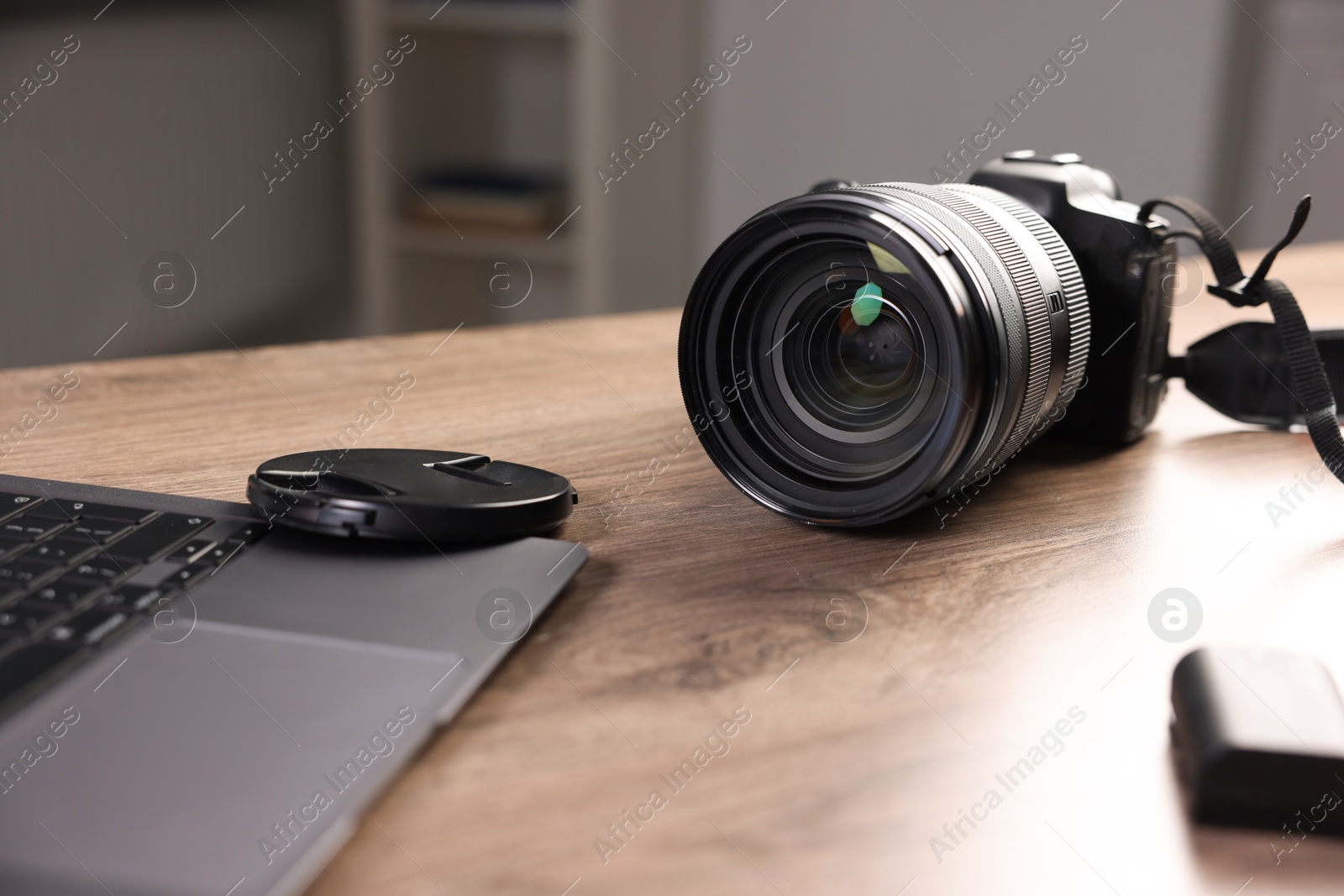 Photo of Professional photo camera and laptop on wooden desk indoors