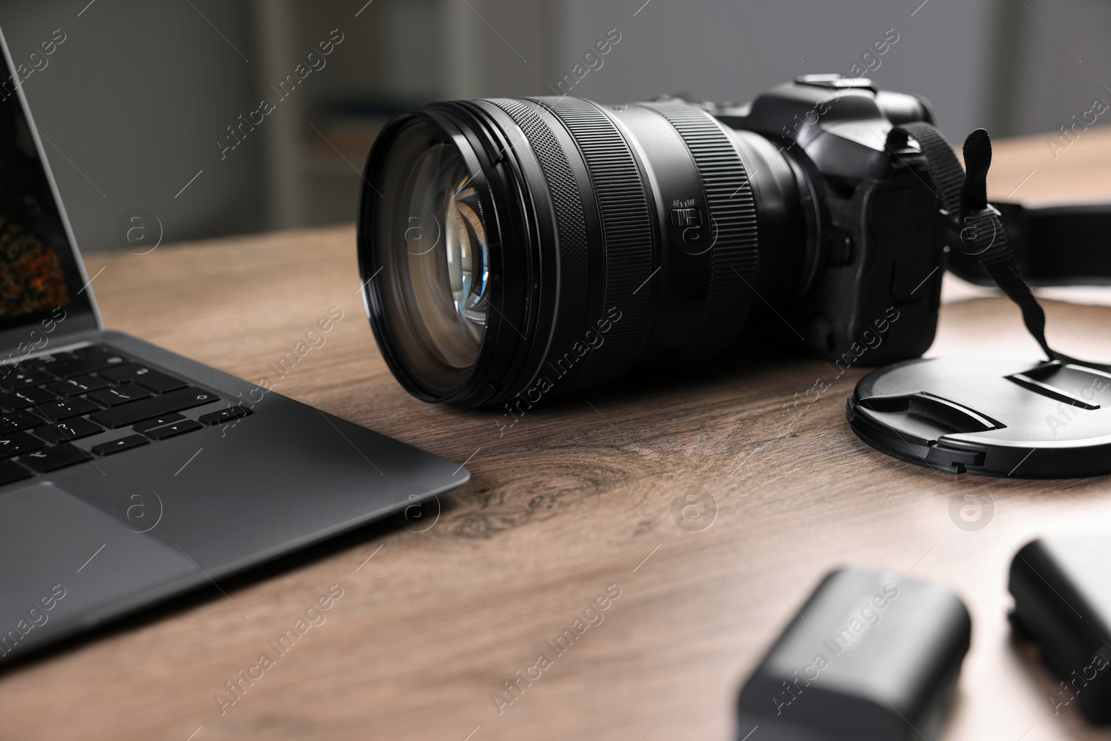 Photo of Professional photo camera and laptop on wooden desk indoors