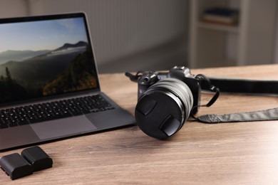 Photo of Professional photo camera and laptop on wooden desk indoors