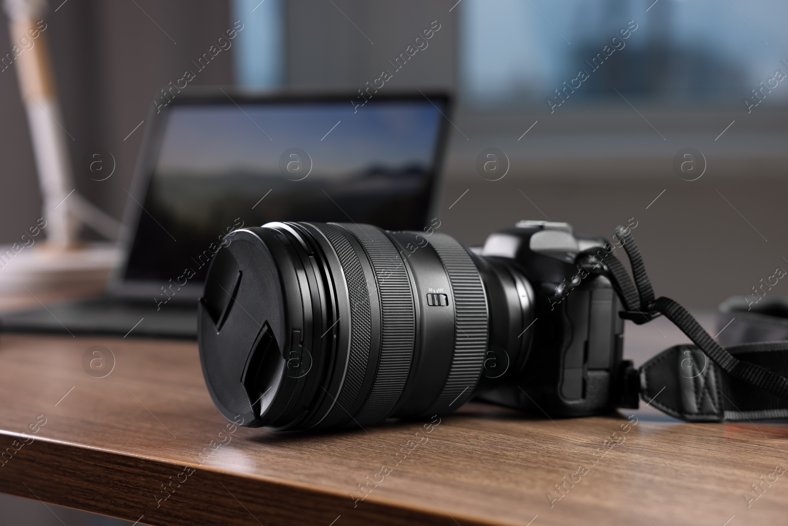 Photo of Professional photo camera and laptop on wooden desk indoors, selective focus