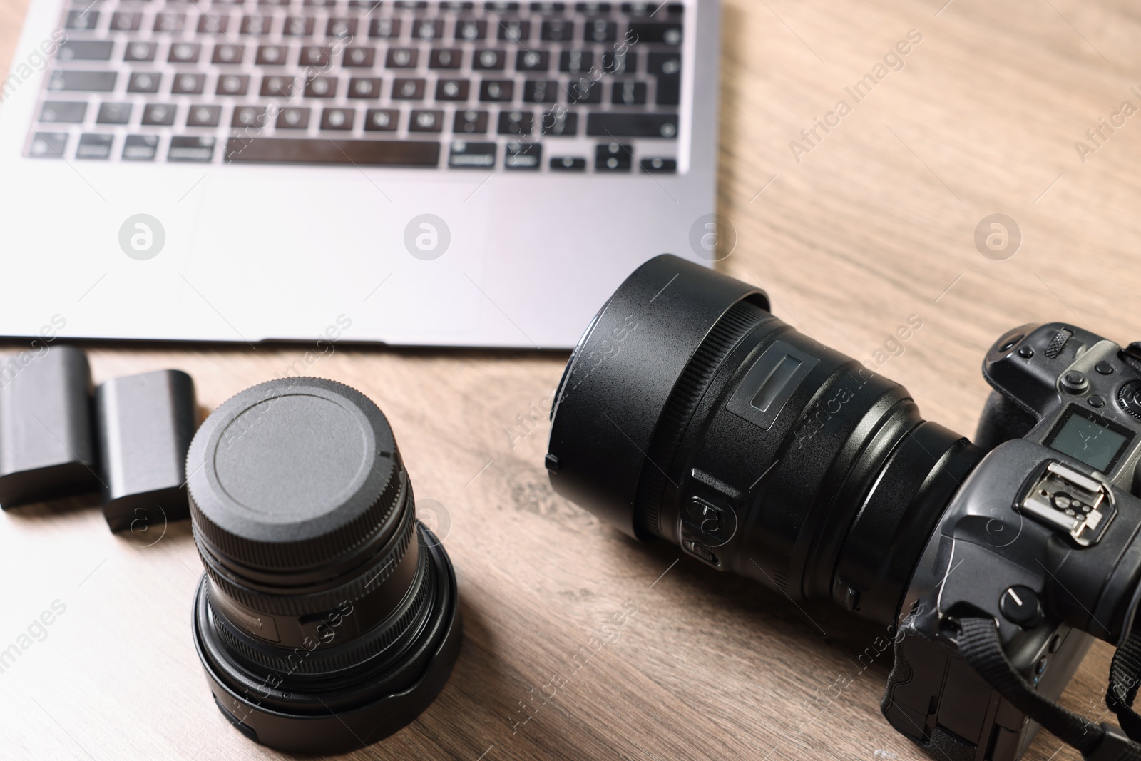 Photo of Professional photo camera, lens and laptop on wooden desk, above view