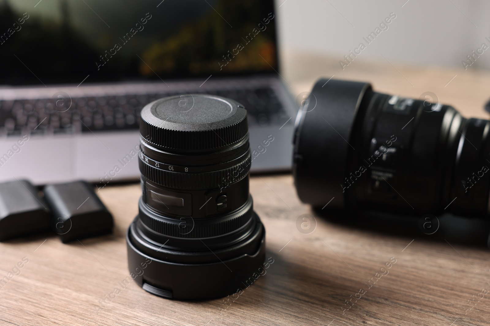 Photo of Professional photo camera, lens and laptop on wooden desk, selective focus