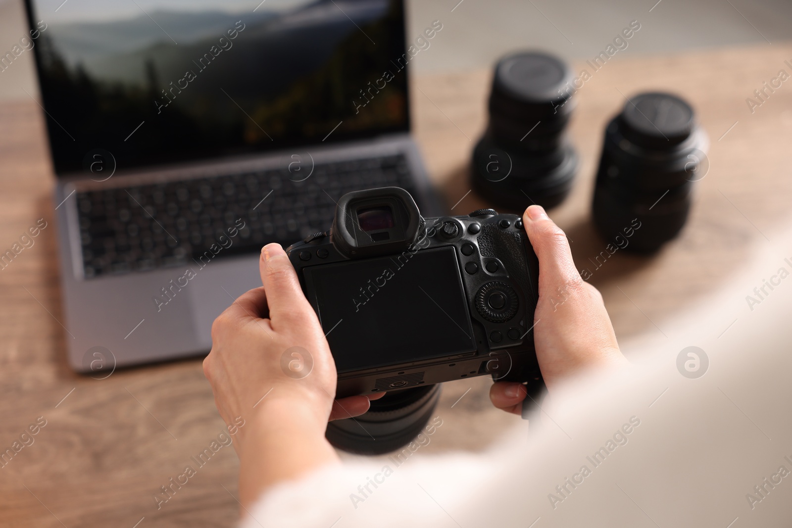 Photo of Photographer with professional camera at wooden desk, closeup