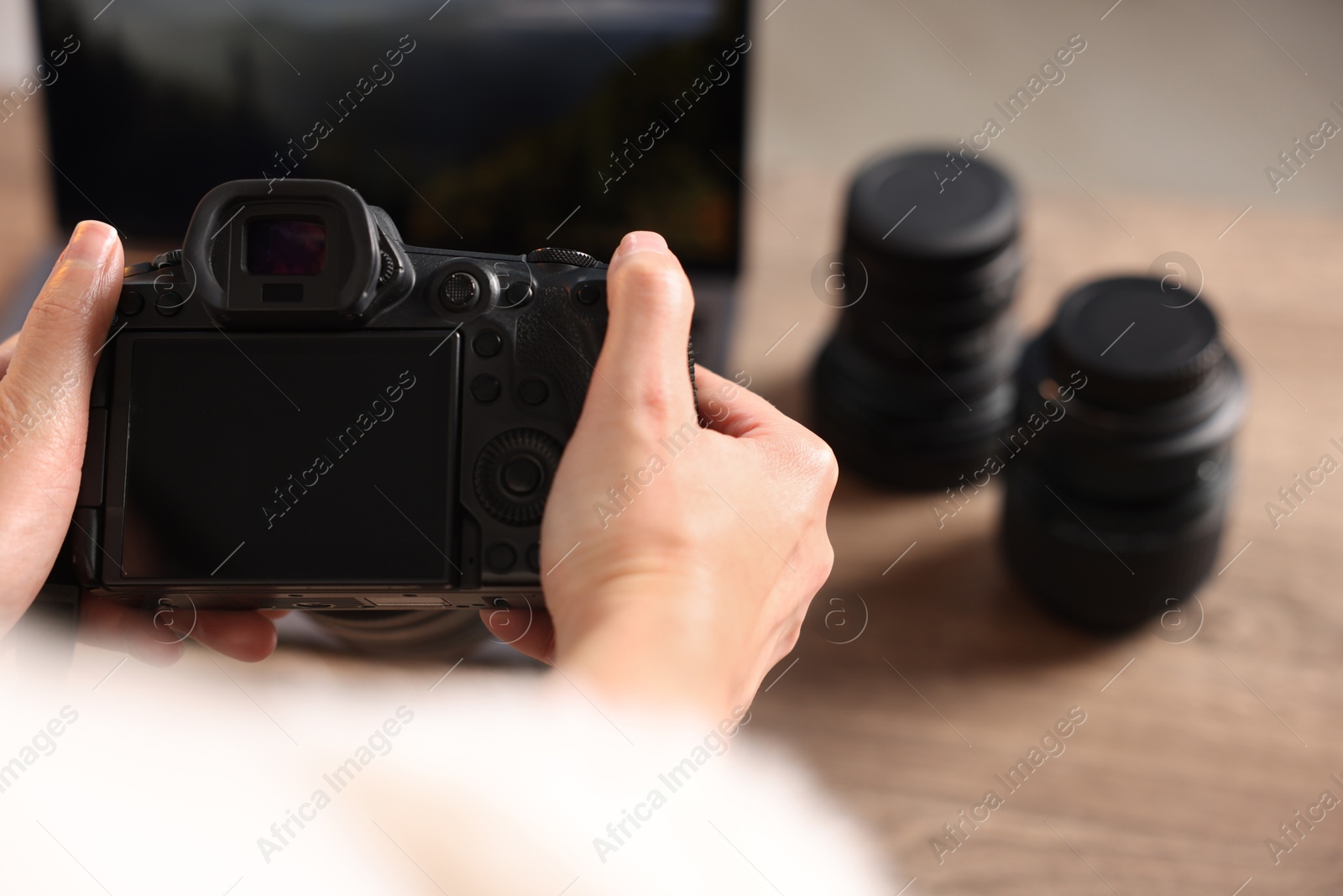 Photo of Photographer with professional camera at wooden desk, closeup