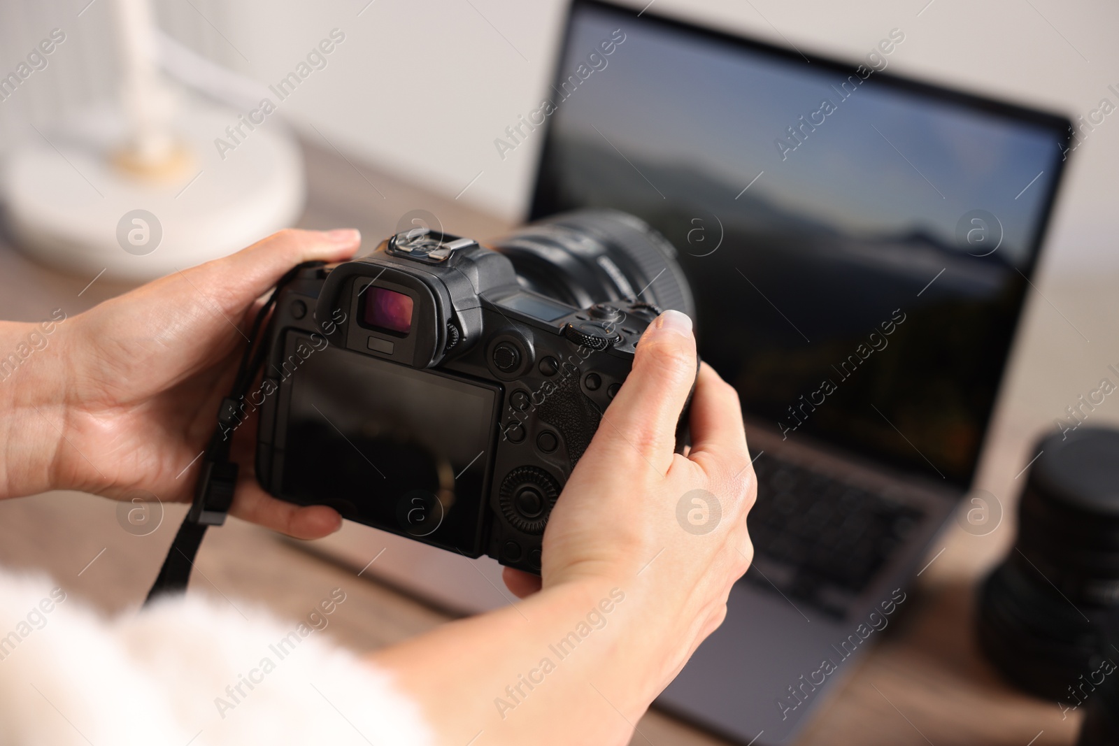 Photo of Photographer with professional camera at wooden desk, closeup