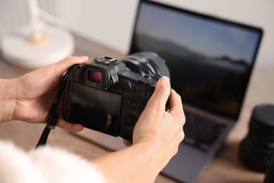 Photo of Photographer with professional camera at wooden desk, closeup