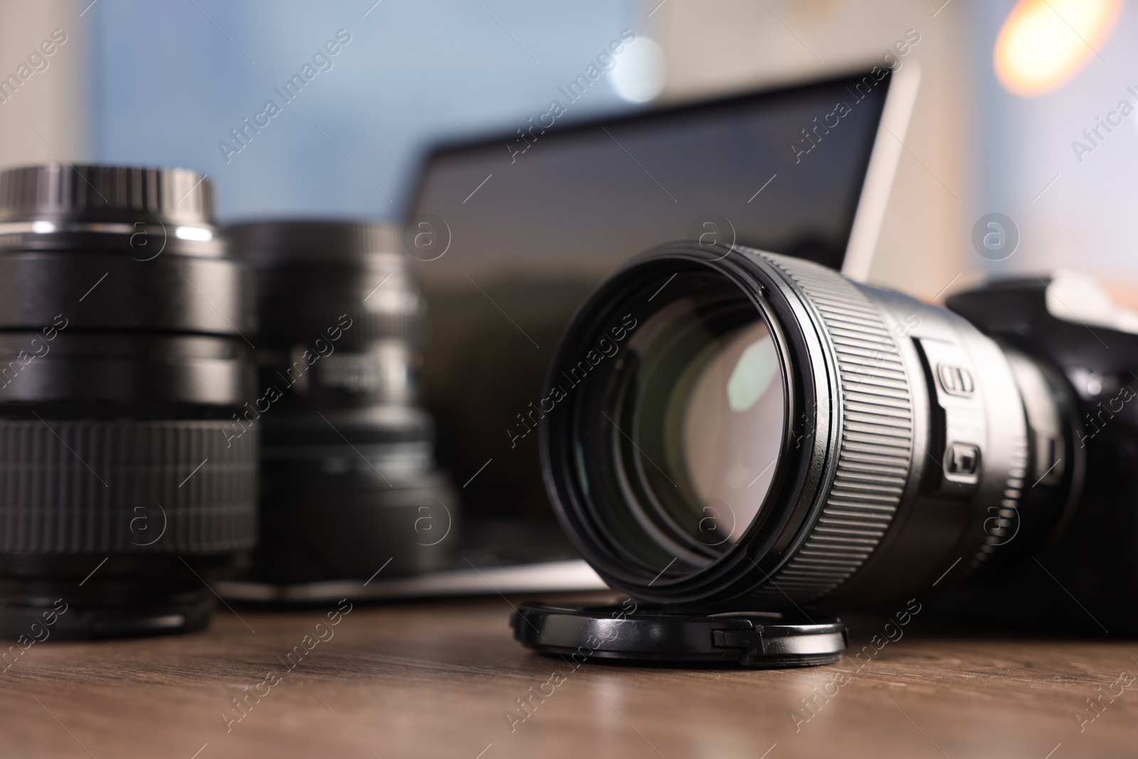 Photo of Professional photo camera, lenses and laptop on wooden desk indoors, selective focus