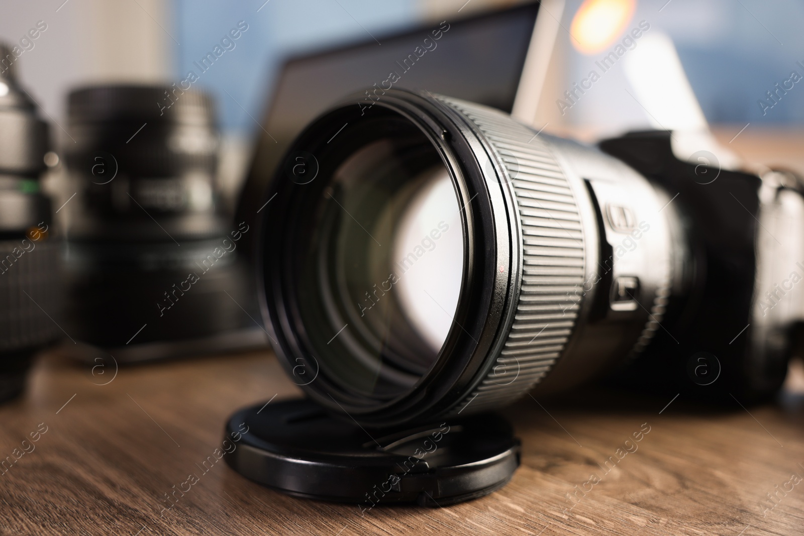 Photo of Professional photo camera, lenses and laptop on wooden desk indoors, selective focus