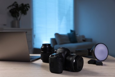 Photo of Professional photo camera, lens, flash and laptop on wooden desk indoors. Space for text