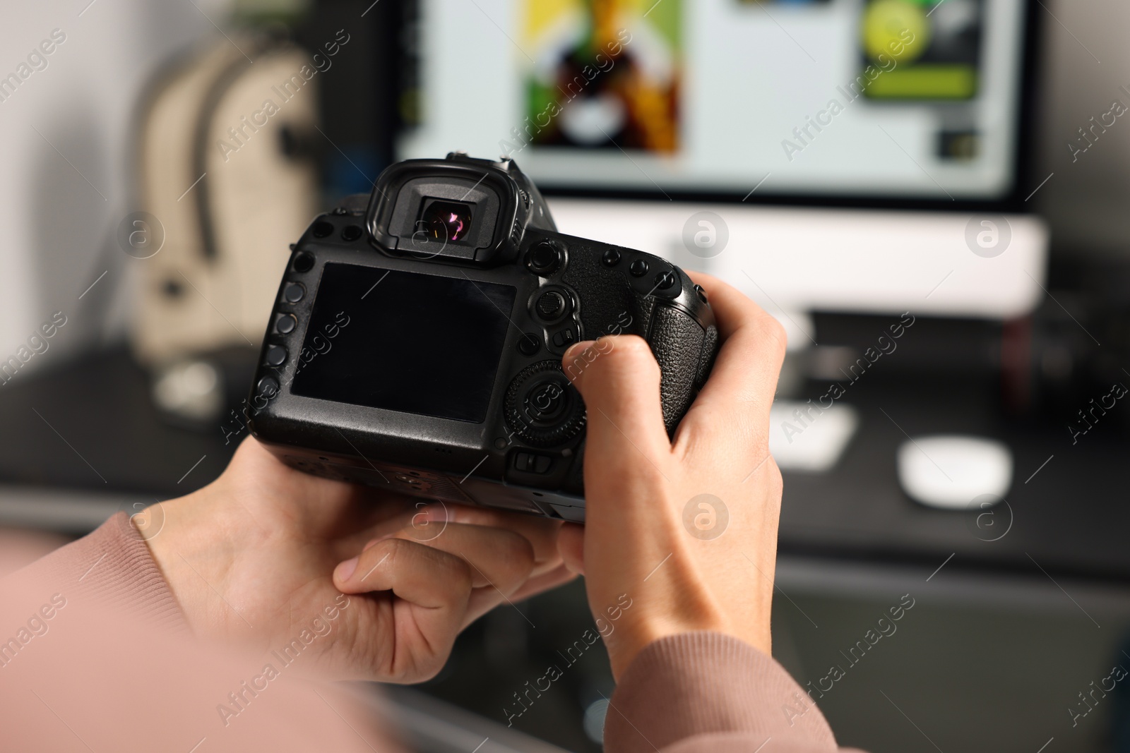 Photo of Photographer with professional camera at desk indoors, closeup