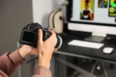 Photo of Photographer with professional camera at desk indoors, closeup