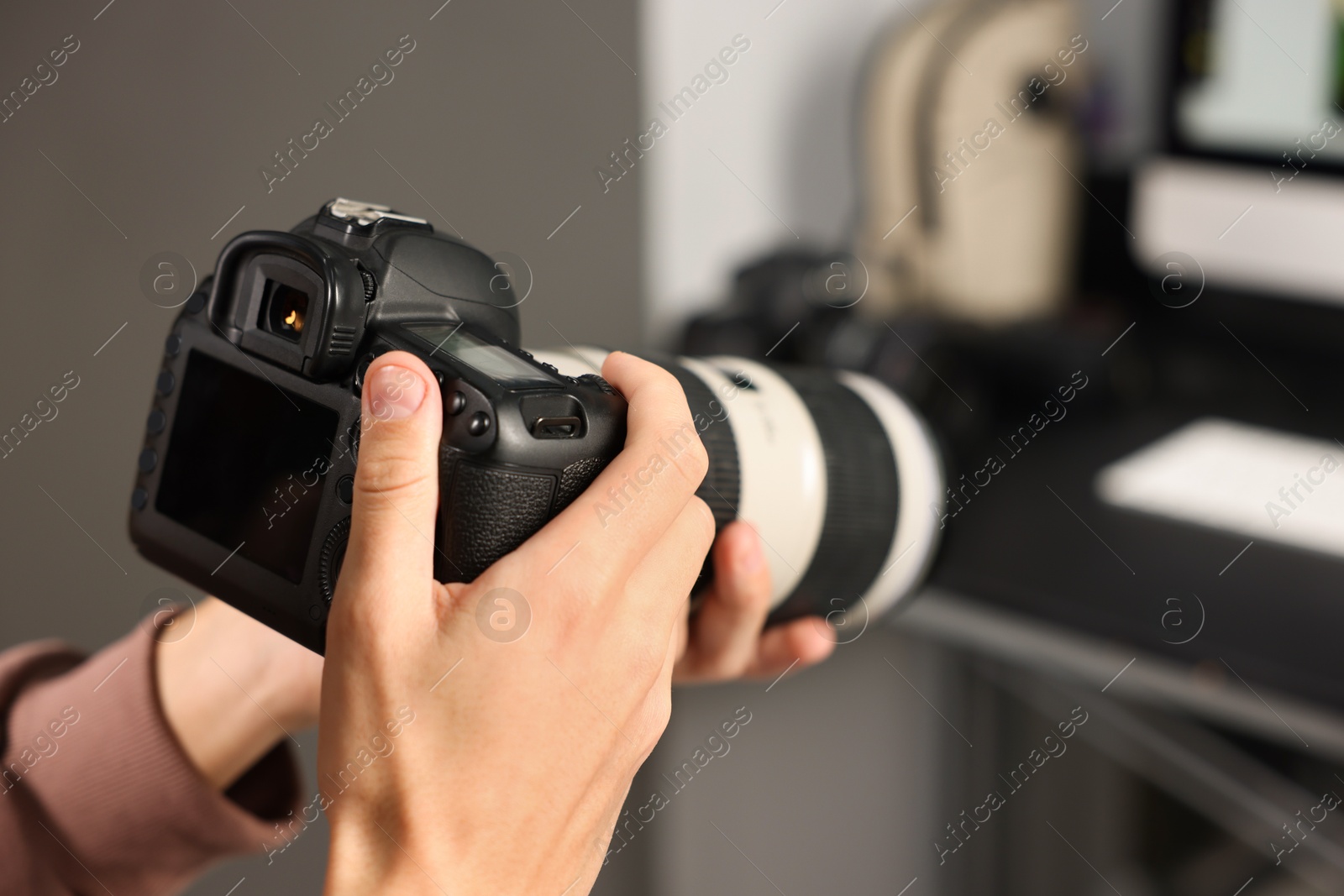 Photo of Photographer with professional camera at desk indoors, closeup