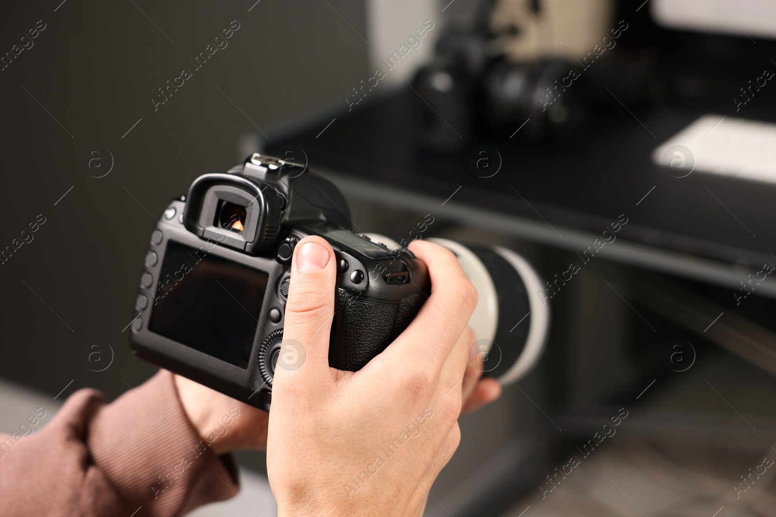 Photo of Photographer with professional camera at desk indoors, closeup