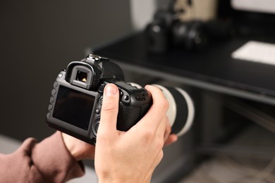 Photo of Photographer with professional camera at desk indoors, closeup