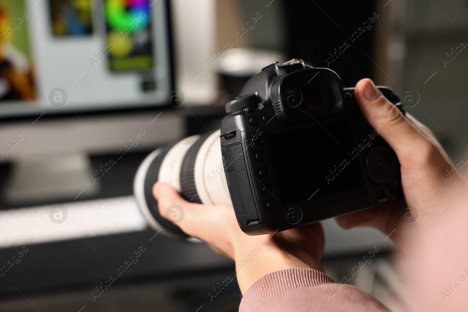 Photo of Photographer with professional camera at desk indoors, closeup