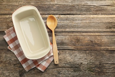 Photo of Ceramic casserole and spoon on wooden table, top view. Space for text