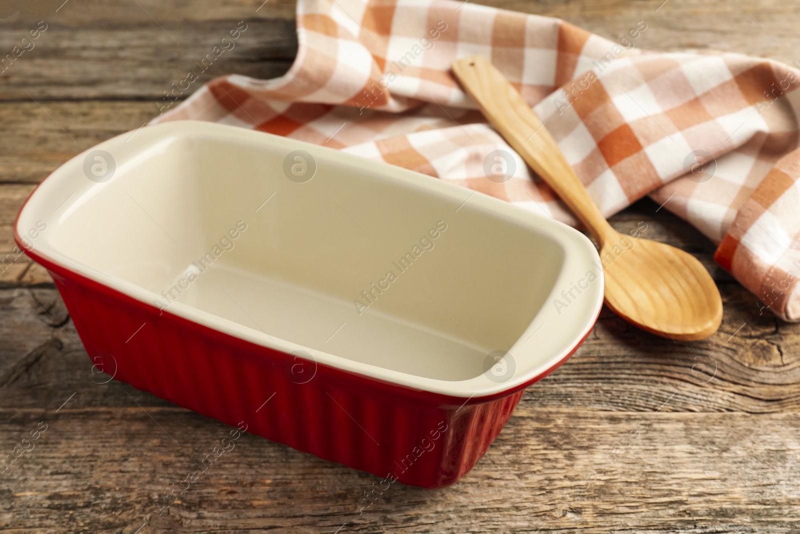 Photo of Ceramic casserole and spoon on wooden table, closeup