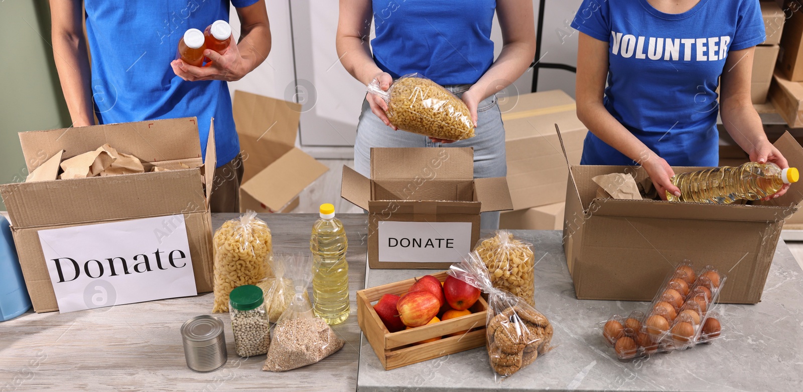 Photo of Volunteers packing food donations at tables indoors, closeup