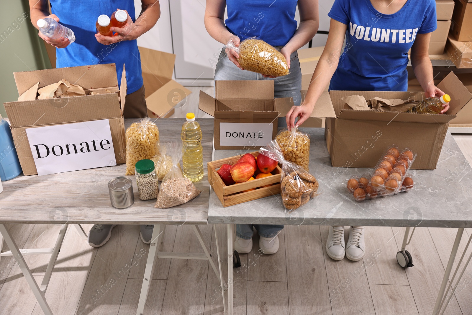 Photo of Volunteers packing food donations at tables indoors, closeup