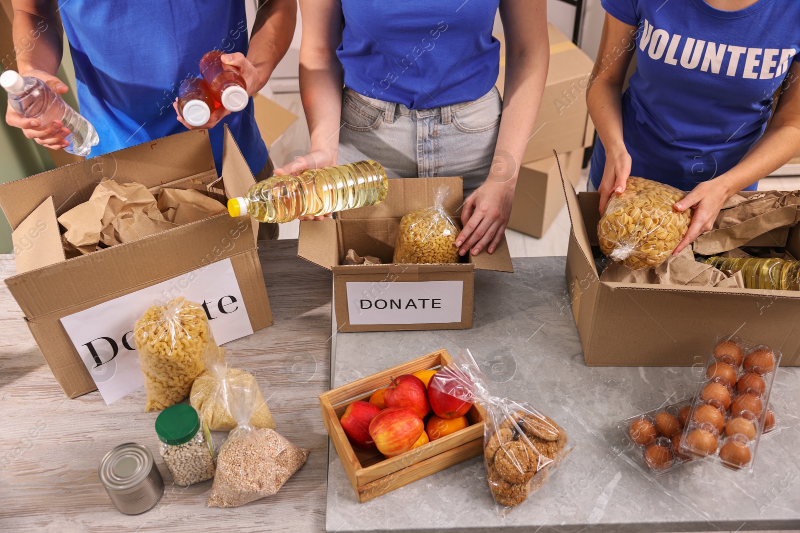 Photo of Volunteers packing food donations at tables indoors, closeup